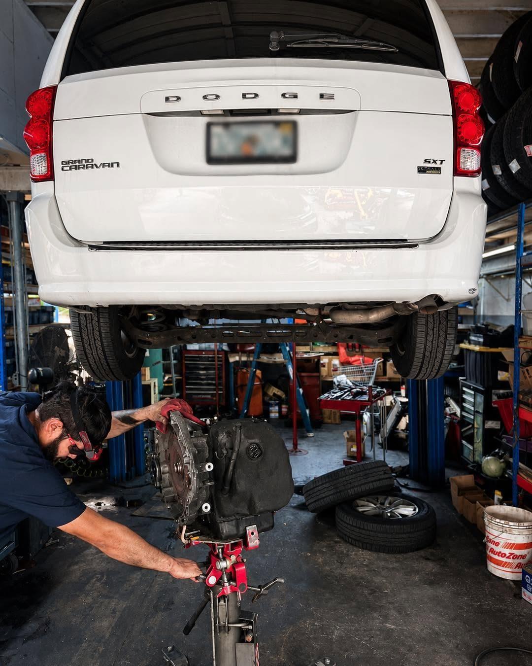 Technician removing the transmission from a Dodge Grand Caravan on the lift